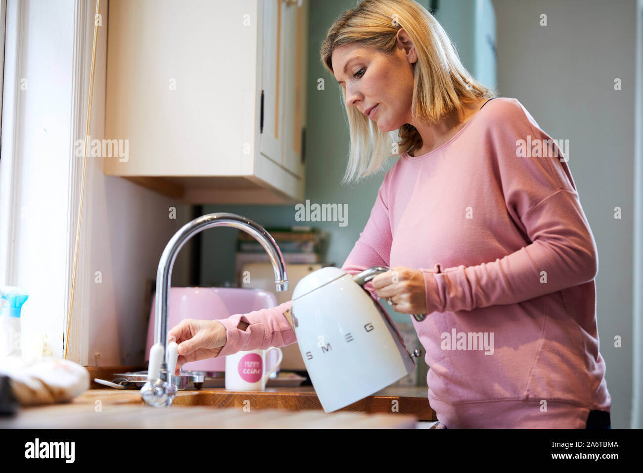 Donna riempire il bollitore con acqua Foto Stock