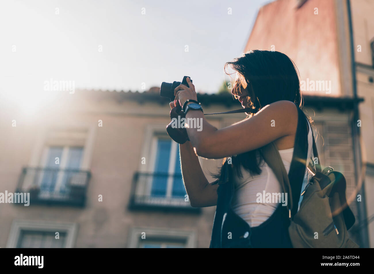 Persona di sesso femminile con un sacchetto facendo una foto con la sua fotocamera reflex al tramonto Foto Stock