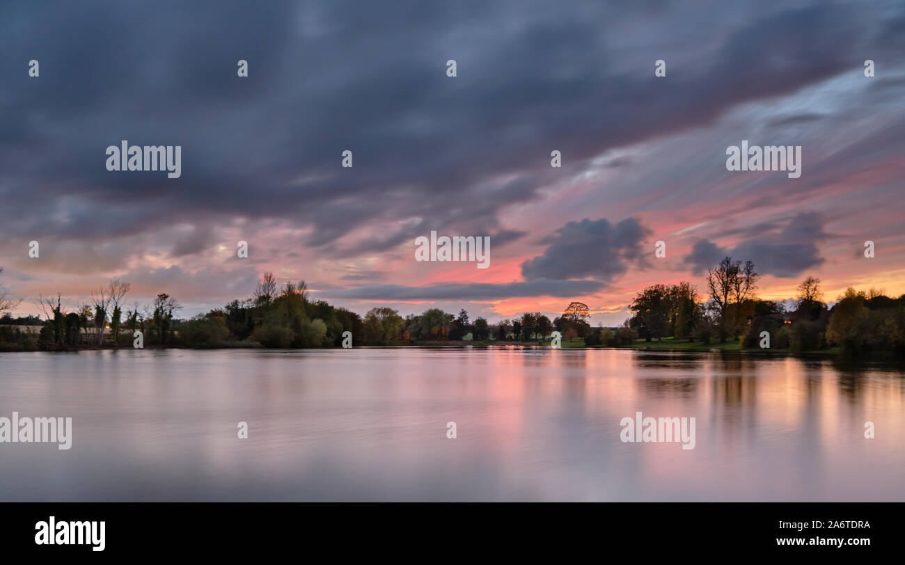 Tramonto autunnale con riflessioni su un viale alberato Culverthorpe lago nel Lincolnshire paesaggio rurale Foto Stock