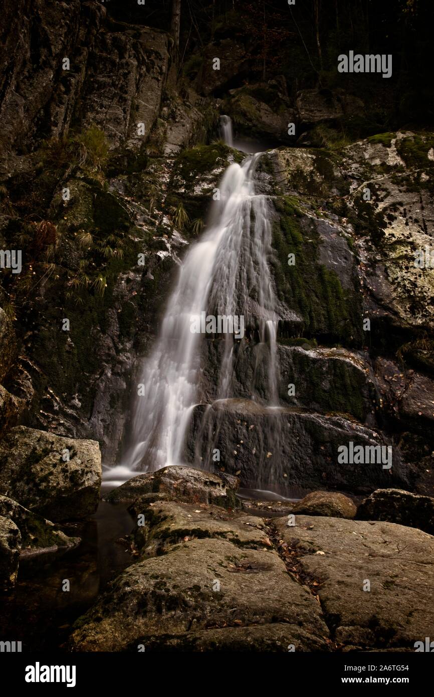 Autunno lunga esposizione del Creek e nero (grande) Stolpich cascate in Jizera Mountain. L'acqua cade in un profondo canyon di foresta piena di pietre di granito Foto Stock