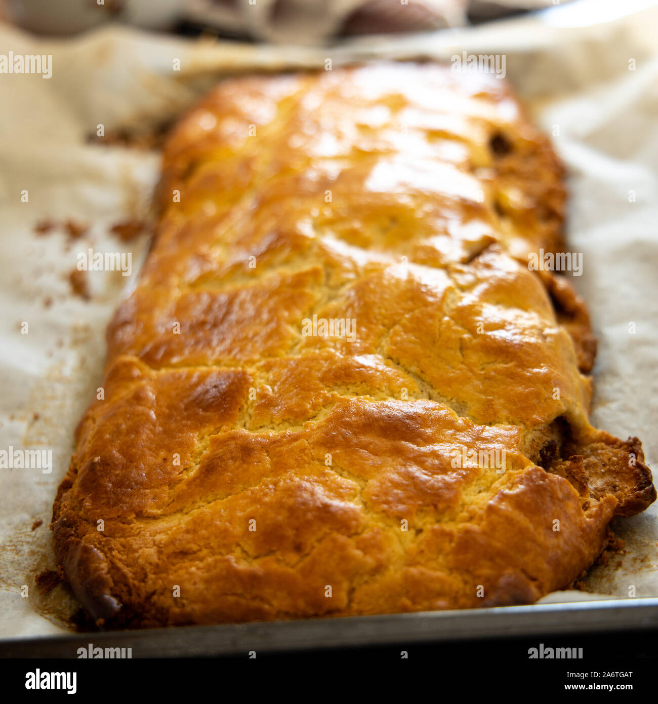 Strudel di mele fresco da una ricetta da South-Tirol giacente su una teglia da forno Foto Stock