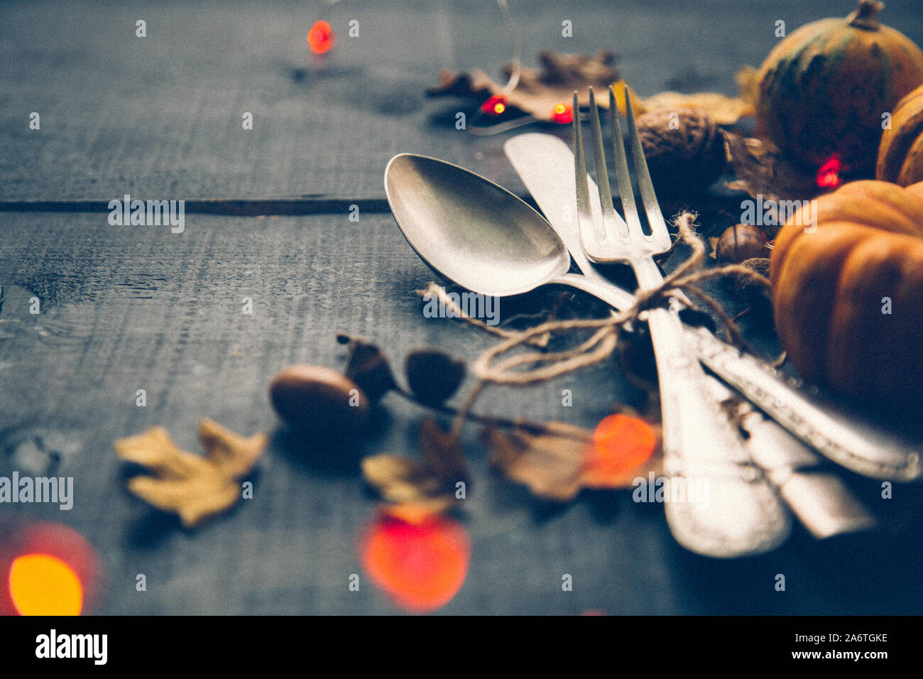 Cena di ringraziamento concetto con vecchie posate, zucche, foglie secche e orange ghirlanda di luci sul blu di un tavolo di legno. Grana di pellicola aggiunti Foto Stock