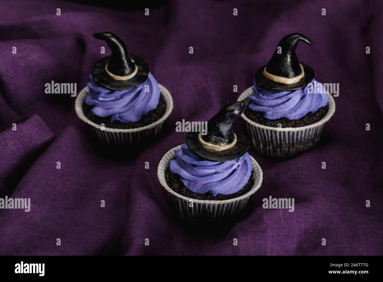Gustosi tortini di Halloween con blu e crema di Strega decorativo cappelli sul panno viola Foto Stock