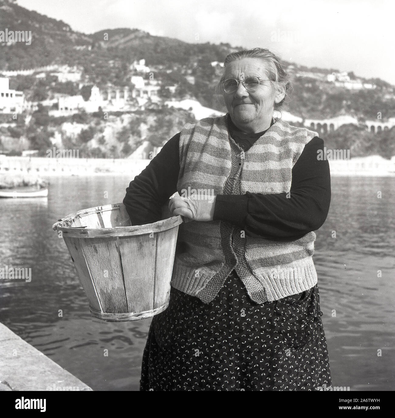 1950, storica, un'anziana signora francese con un secchio di legno in piedi su una banchina sulla costa mediterranea a Nizza, Francia, fotografata da J. Allan Cash. Foto Stock