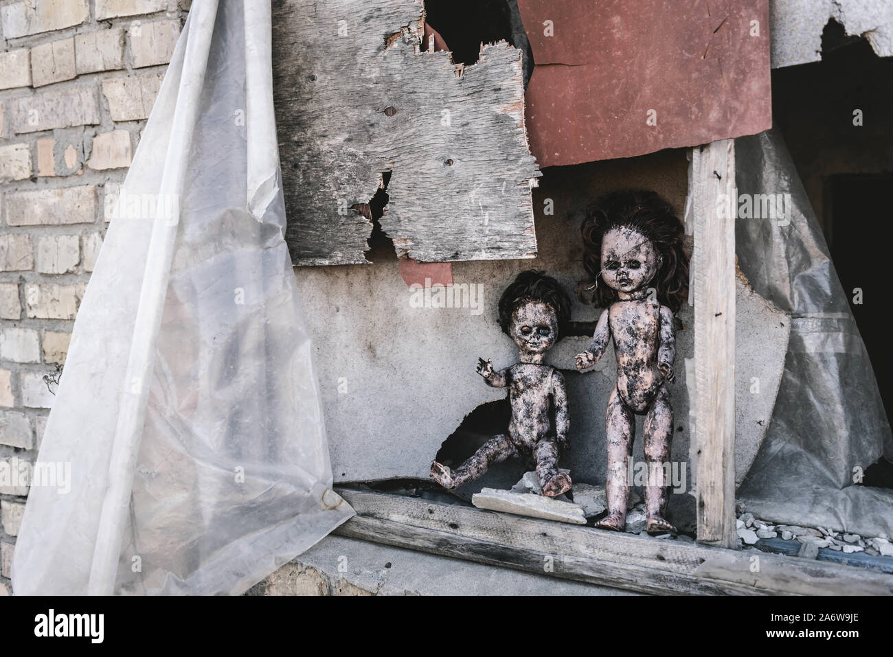 Scary e bruciato baby dolls vicino alla finestra arrugginito, post concetto apocalittico Foto Stock