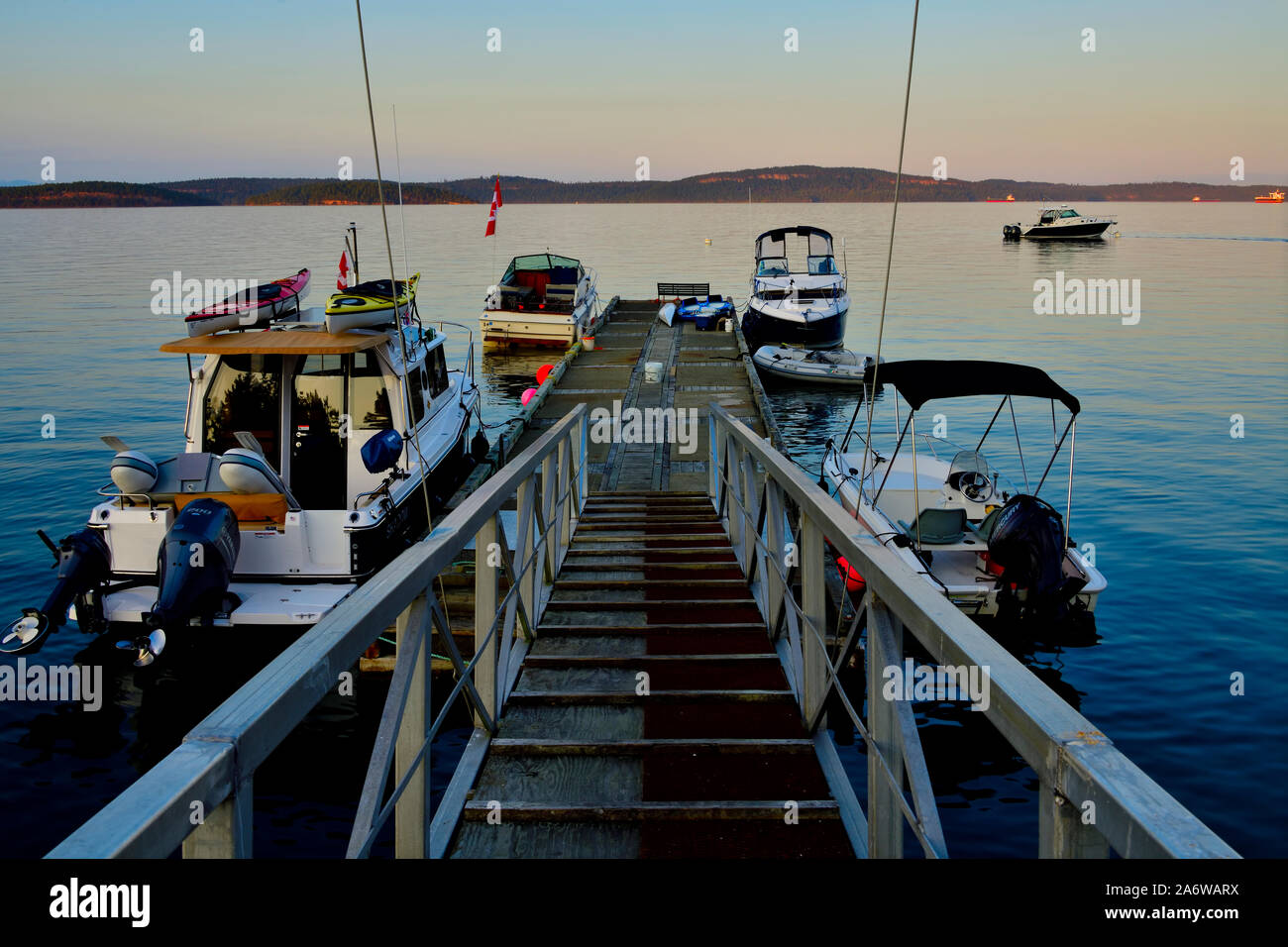 Un molo aggettante internamente al canale di Stewart caricato con imbarcazioni da diporto su una tranquilla serata d'estate sull'Isola di Vancouver British Columbia Canada. Foto Stock
