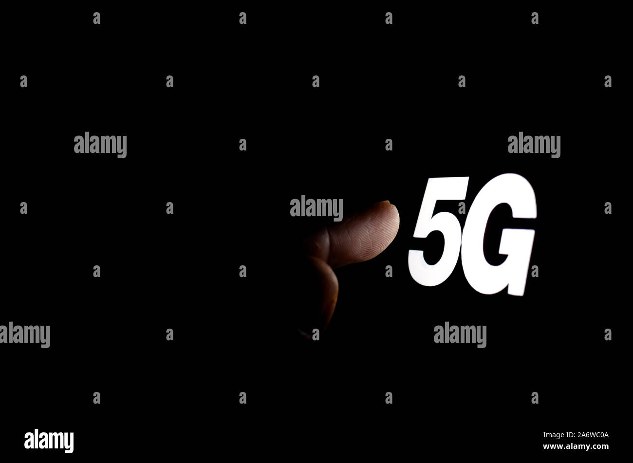 5G lettere incandescente sullo schermo dello smartphone e la mano di raggiungere per esso. Il concetto foto per 5G wireless network. Foto Stock