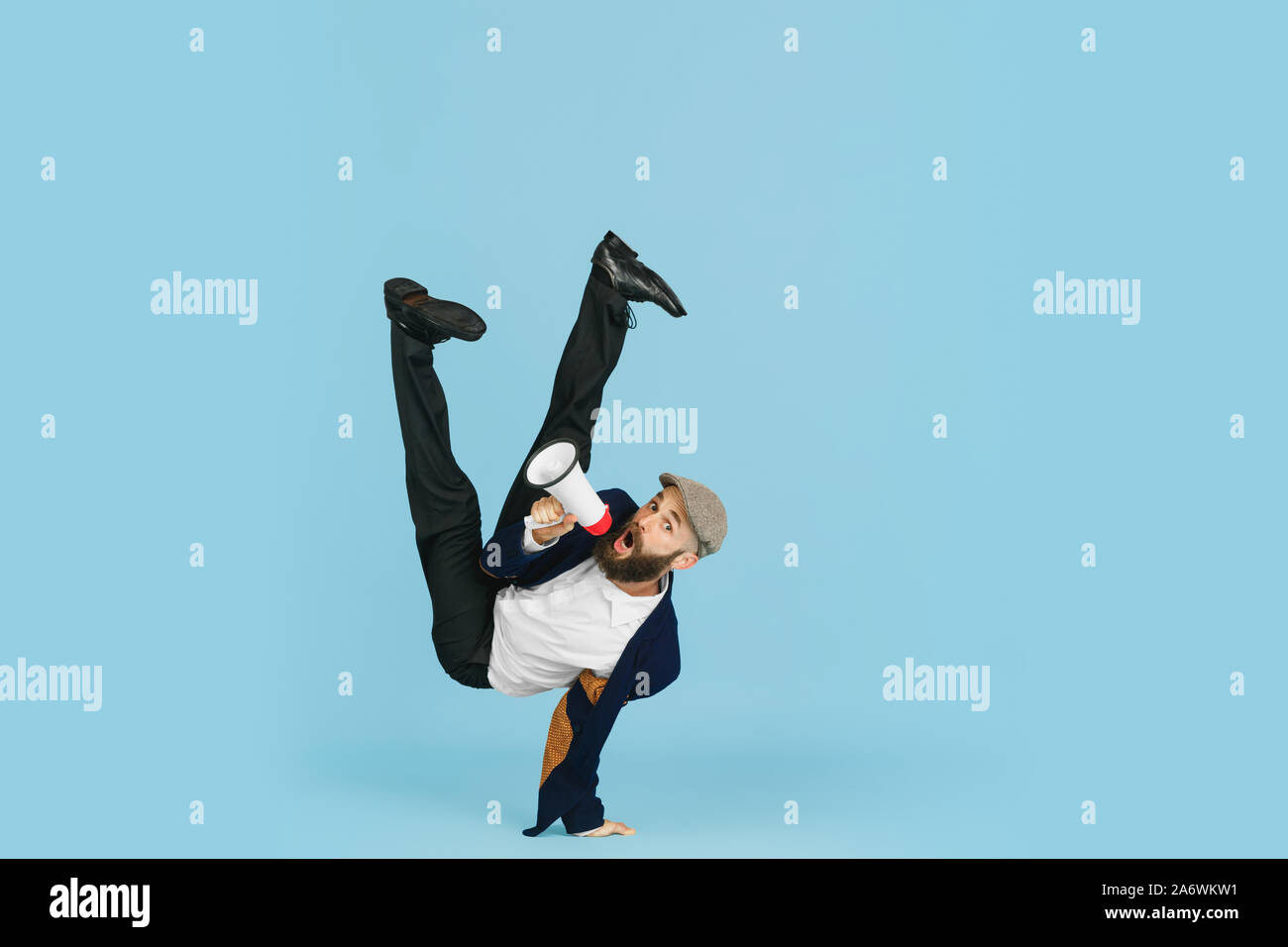 Giovane imprenditore caucasico divertirsi ballare break dance su blu di sfondo per studio. Gestione, flessibile, libertà, attività professionale, un modo alternativo di lavoro moderno. Ama il suo lavoro. Copyspace. Foto Stock