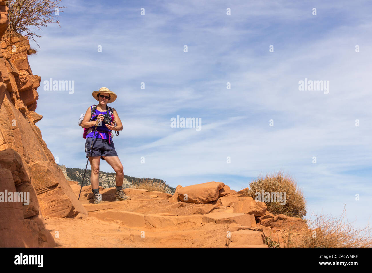 Donna escursionismo da sola il South Kaibab Trail nel Grand Canyon sotto un cielo blu su uno stretto e pericoloso sentiero Foto Stock