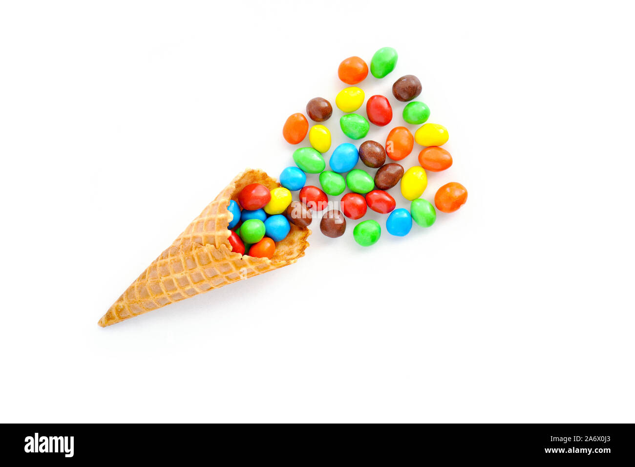 Candy coperto arachidi fuoriuscita dal cono di cialda su sfondo bianco. Nel piano di composizione dei laici con una stanza per il testo. Foto Stock