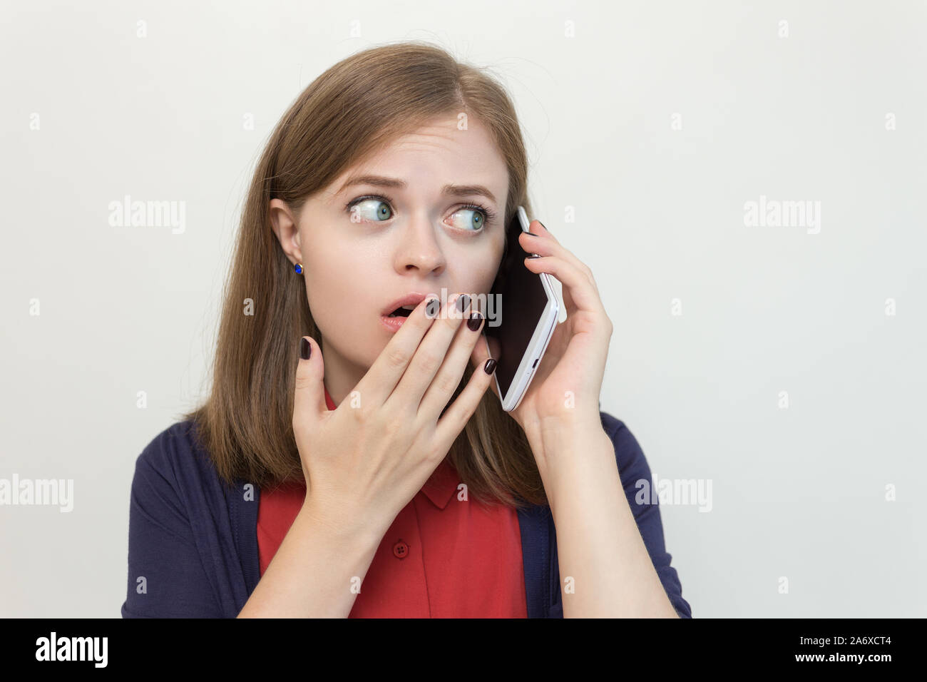 Giovane ragazza caucasica donna sta parlando al telefono cellulare, appare spaventato, sconvolto, preoccupato o triste Foto Stock
