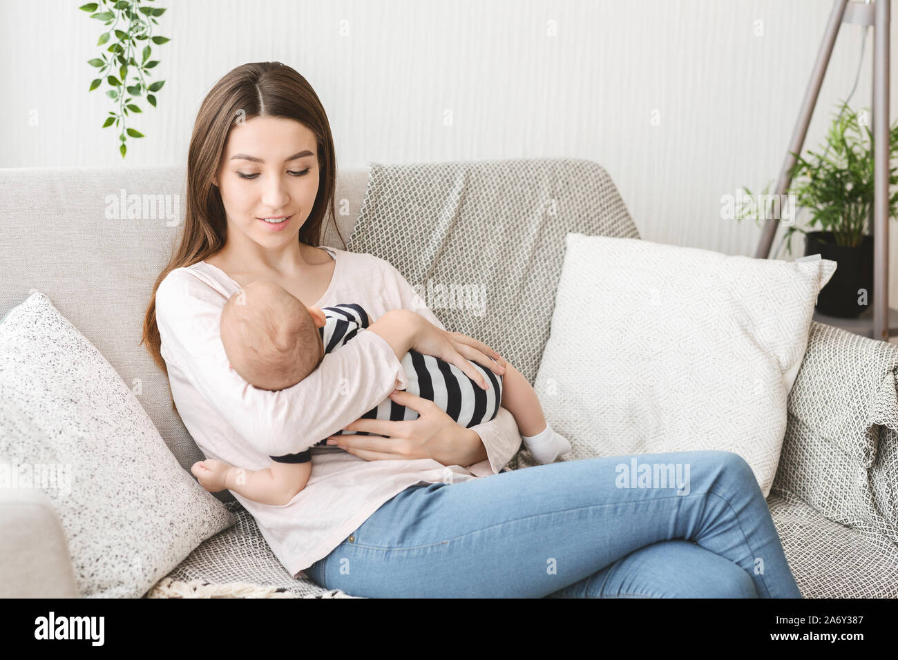 Azienda mom neonato, Lulling bambino su couh a casa Foto Stock
