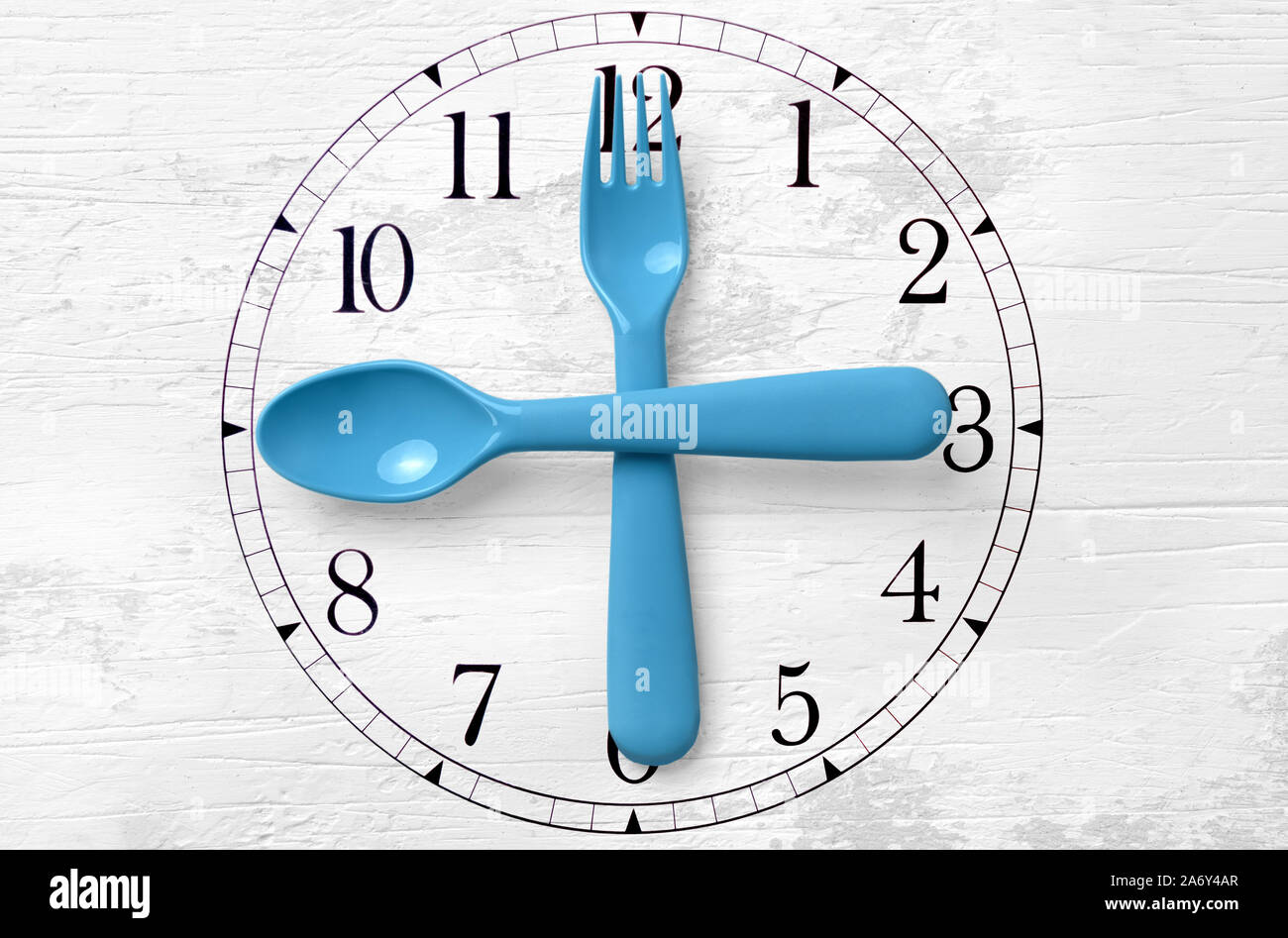 Orologio sul tavolo con le mani cucchiaio e forchetta Foto Stock