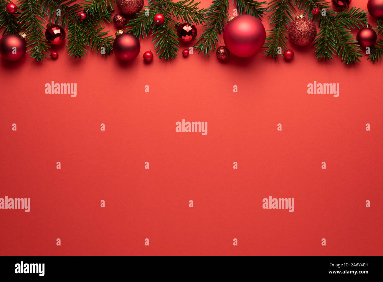 Sfondo rosso con le palle di Natale e rami di abete. Auguri di Buon Natale o Capodanno decorazione con spazio di copia Foto Stock