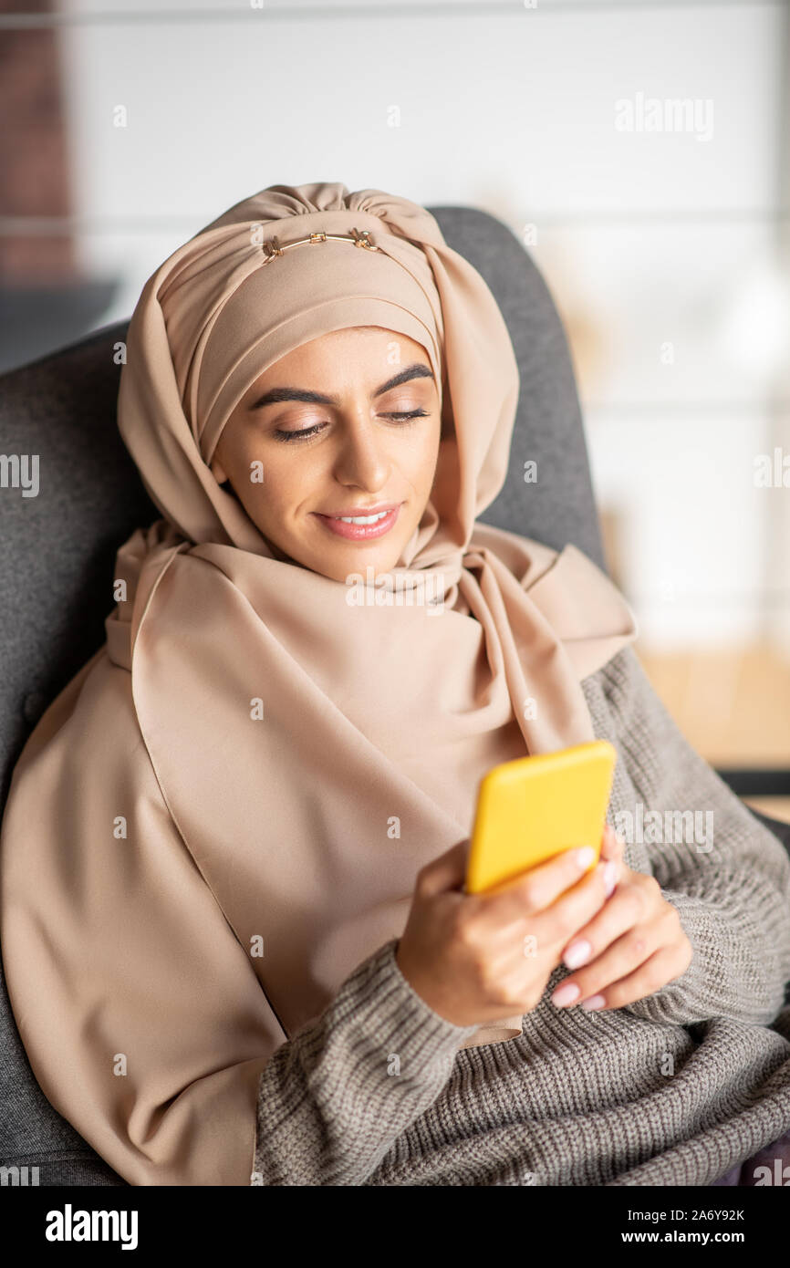 Bella ragazza musulmana abbattimento felice mentre usando il telefono Foto Stock