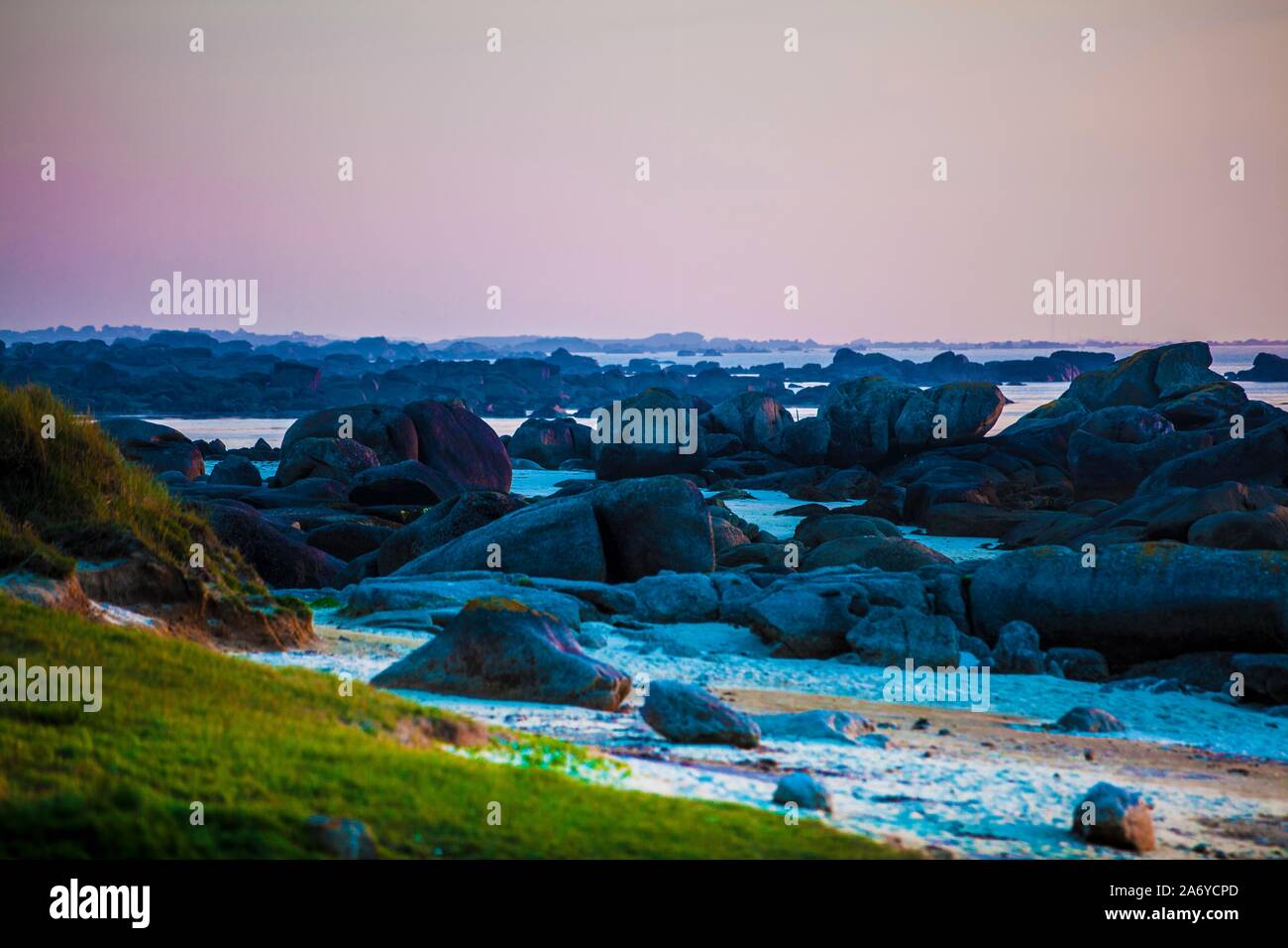 Die felsige Küste am Pointe de Pontusval in der Bretagne. Es ist in der Abenddämmerung, die letzten Sonnenstrahlen tauchen die risigen Felsen am Stran Foto Stock