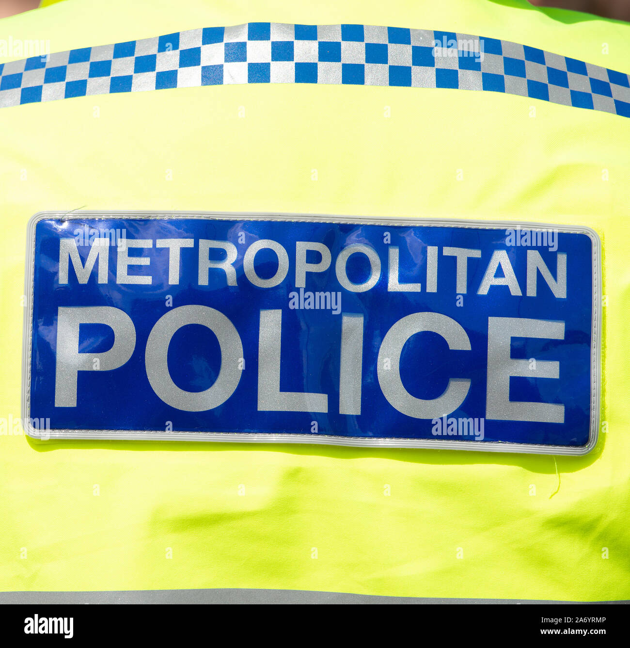 Primo piano del cartello della polizia Metropolitana indossato sul retro di una giacca ad alta visibilità, da un ufficiale che cammina il ritmo nel centro di Londra, Inghilterra. Foto Stock