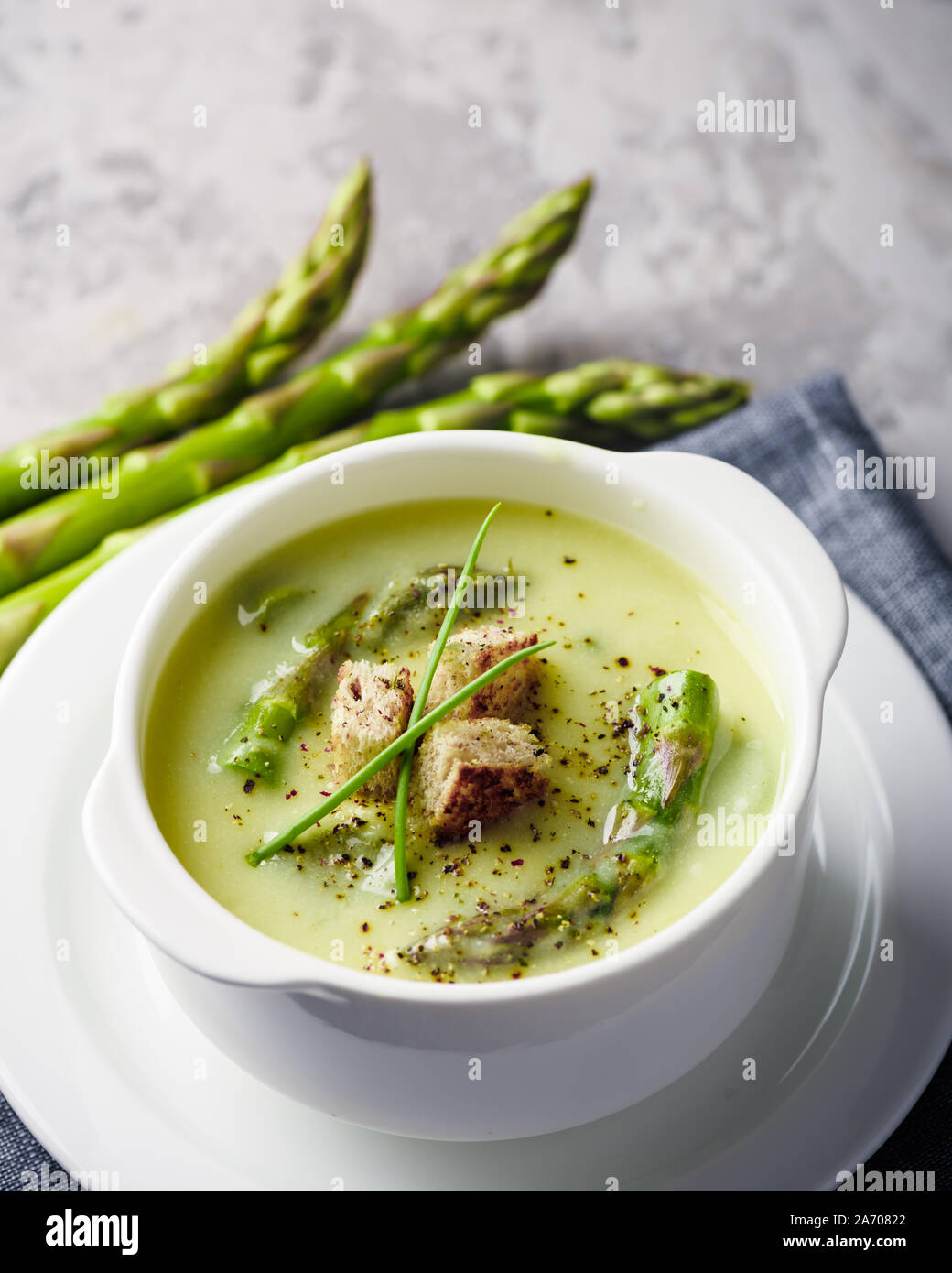 Verde zuppa di asparagi con i cracker in bianco ciotola closeup. Fotografia di cibo Foto Stock