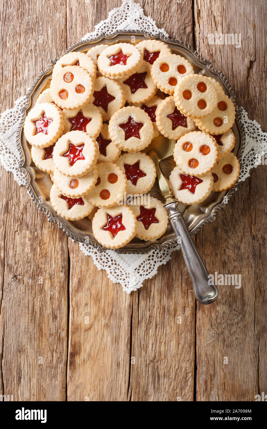 Natale Linzer biscotti farciti con fragola e confettura di albicocca close-up sulla piastra della tavola. Verticale in alto vista da sopra Foto Stock