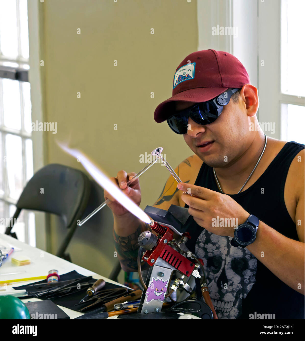 Un maschio lampworker utilizza una torcia per la moda dei tubi di vetro in vetro oggetti d'arte. Arts Festival viva 2019 nel Corpus Christi, Texas USA. Foto Stock