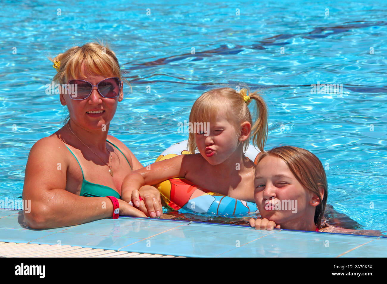 Felice madre divertirsi saltando con le sue figlie sull'erba verde. La famiglia felice team. Famiglia godendo le vacanze estive. Le persone che si godono la vacanza con la famiglia Foto Stock