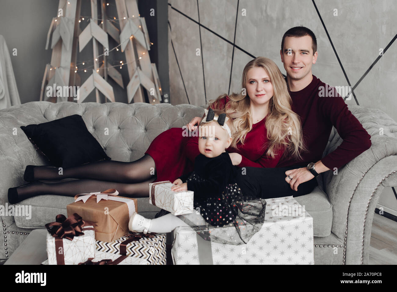 Allegro e gioviale famiglia con bambino sul divano grigio. Foto Stock
