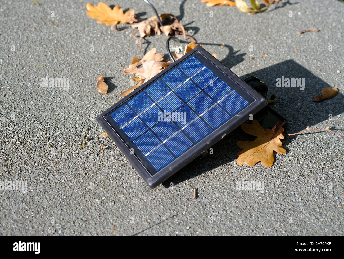 Un piccolo pannello solare per ricaricare un domestico esterno luce di sicurezza. Collocato sotto la luce diretta del sole su un tetto domestico. Foto Stock