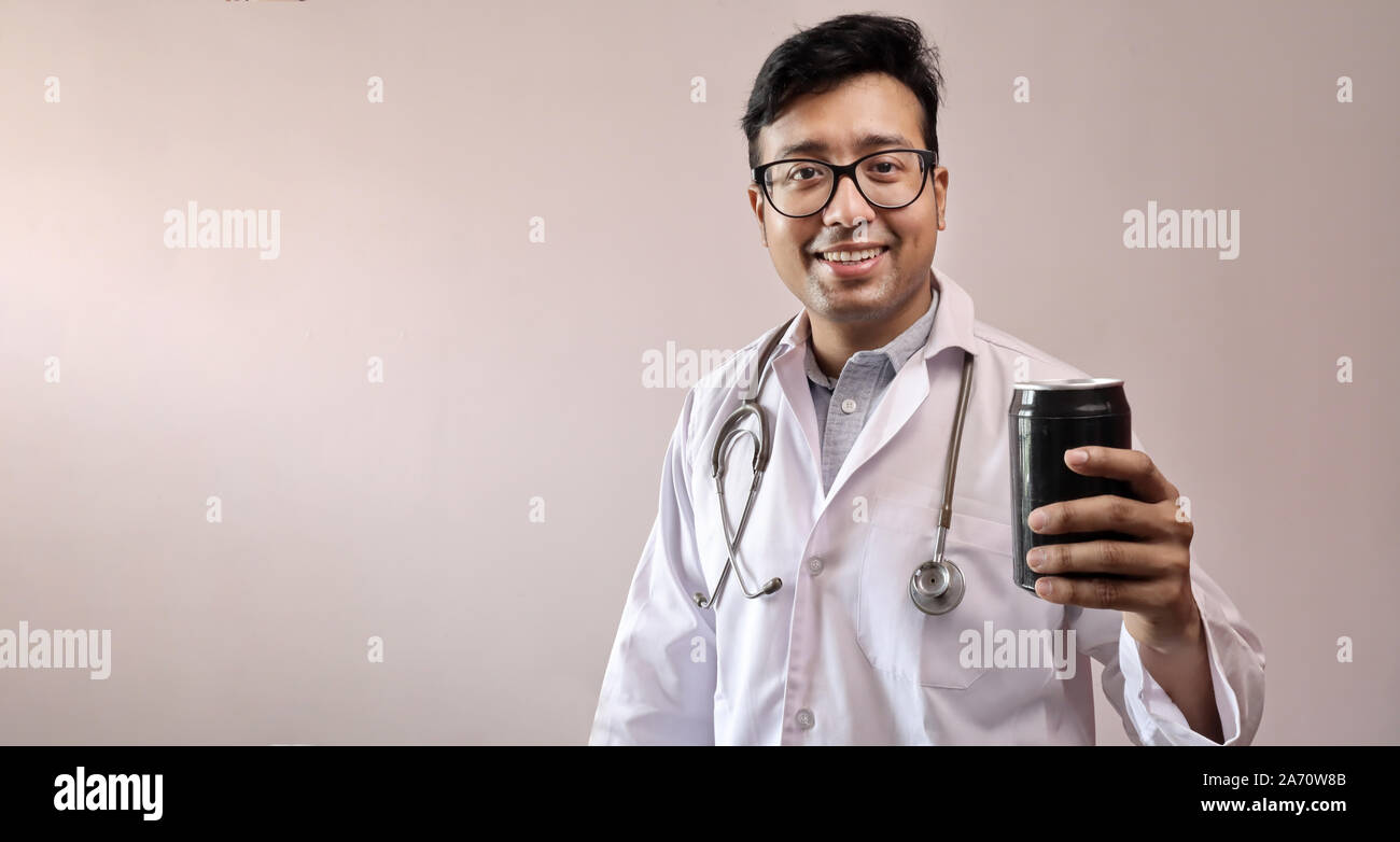 Indiano maschio medico in camice bianco e stetoscopio con una lattina di soda Foto Stock