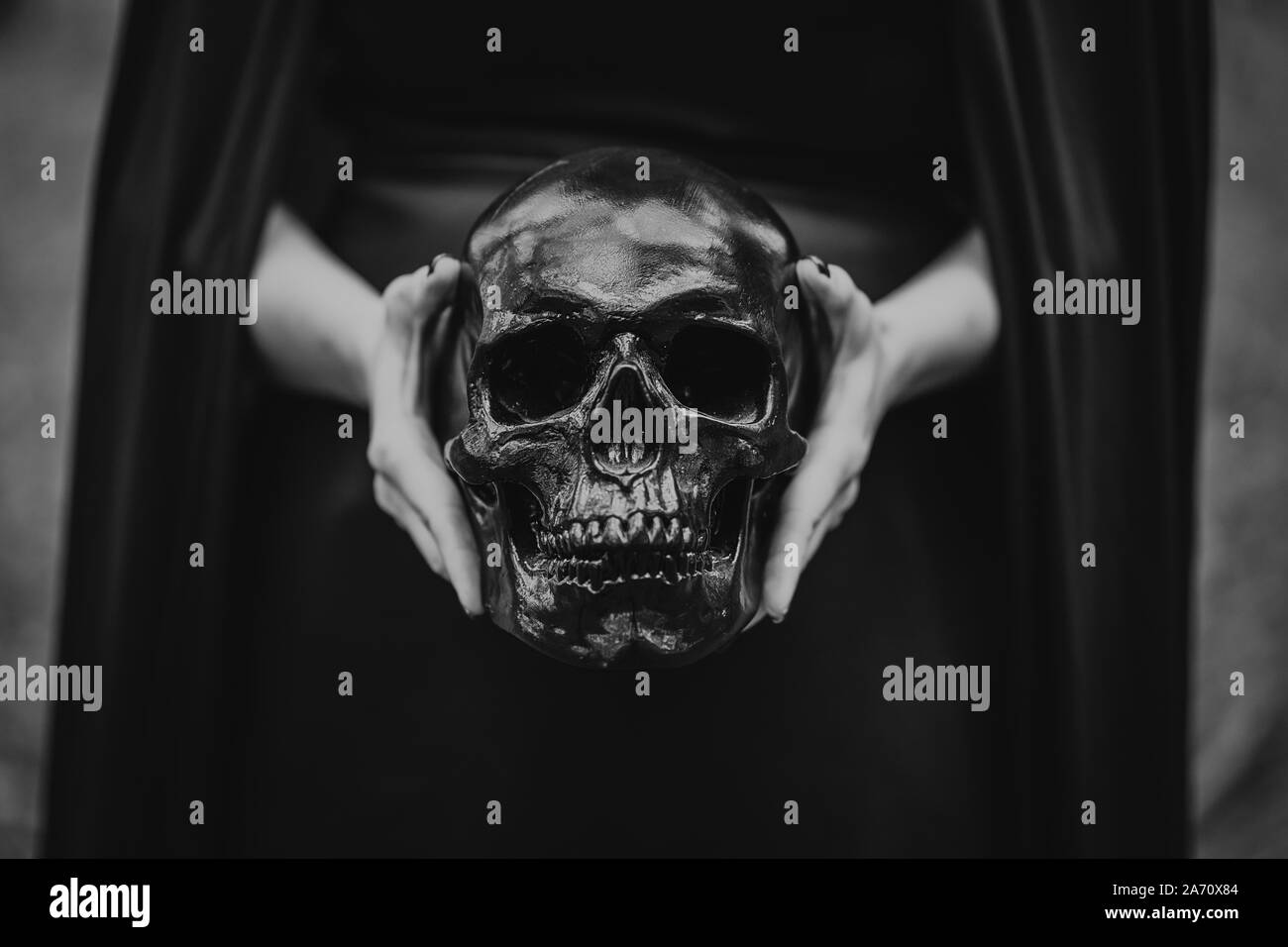 Donna detiene il cranio a mani.La morte, rituali spirituali concetto, Halloween, horror, spaventoso simbolo della morte. In bianco e nero. Foto Stock