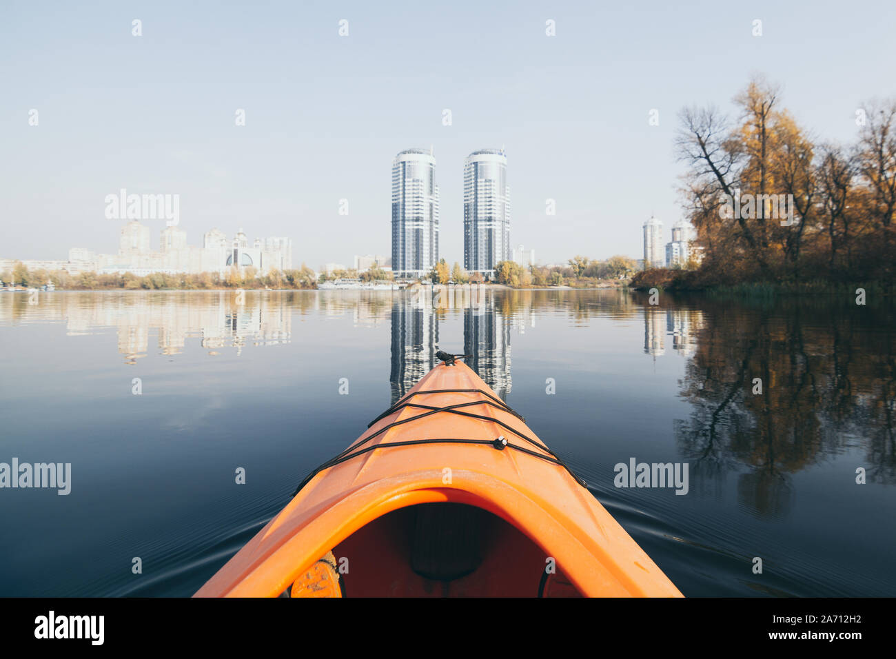 Arancione naso kayak vela verso gli edifici moderni sulle acque del fiume Dnipro a Kiev, Ucraina. Foto Stock