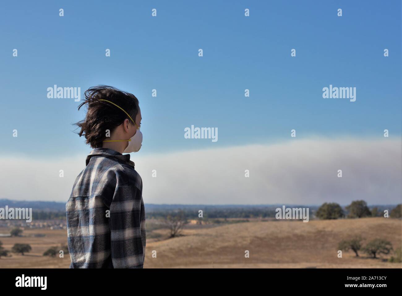 Una giovane ragazza che indossa una maschera di ventilazione si affaccia sul fumo dal Kincade wildfire in Sonoma County, California, Stati Uniti d'America. Foto Stock