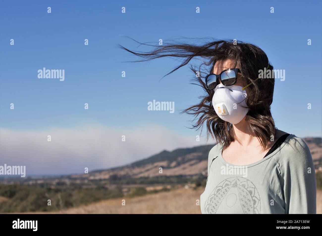 Una donna che indossa una maschera di ventilazione si affaccia sul fumo dal fuoco Kincade in Sonoma County, California, Stati Uniti d'America. Foto Stock