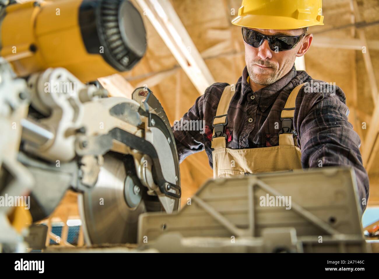 Costruzione caucasica contraente nel suo 30s lavora con Power Tool. Circolare potente Sega da legno. Tema industriale. Foto Stock