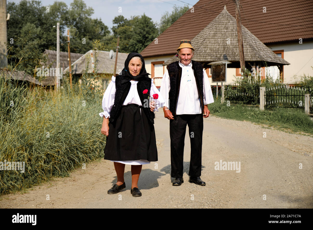 Local Maramures coppia senior a piedi verso la chiesa di domenica i migliori vestiti in Breb, Romania. Lady Rose tenendo a portata di mano Foto Stock