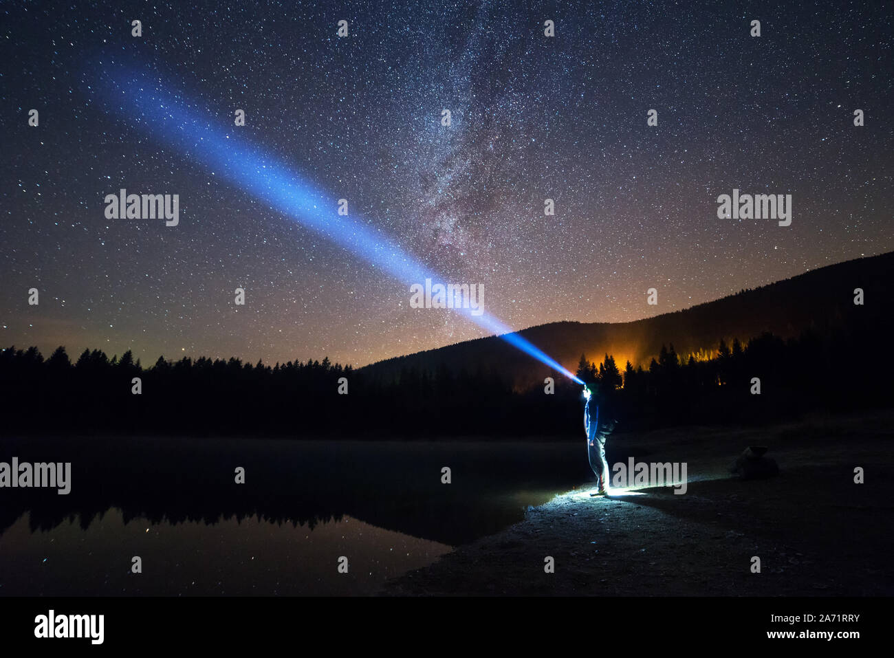 Uomo in piedi sotto il cielo stellato, illuminazione con lampada da testa Foto Stock