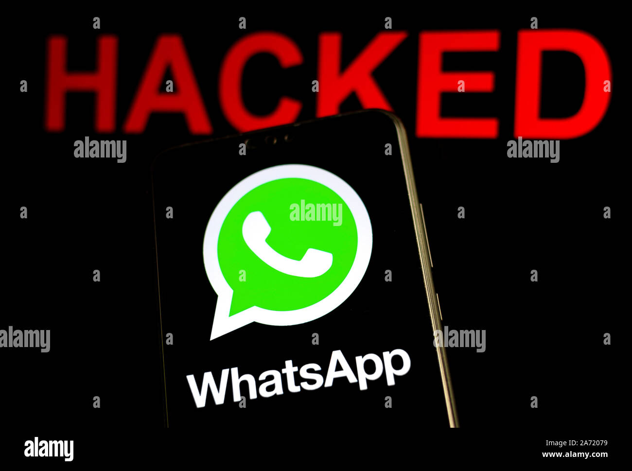 Logo WhatsApp sullo schermo dello smartphone in una stanza buia e la parola 'violato' a sfondo sfocato. Messa a fuoco selettiva. Foto Stock