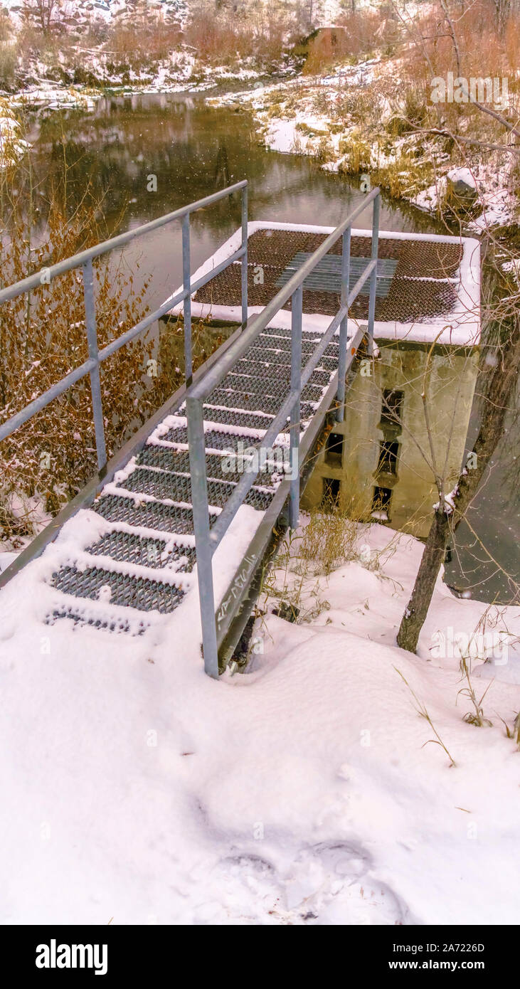 Piattaforma verticale al di sopra dell'uomo fatto area di drain di un piccolo lago nella neve Foto Stock