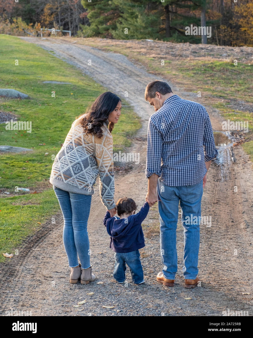 Una famiglia a camminare su una strada sterrata in autunno Foto Stock
