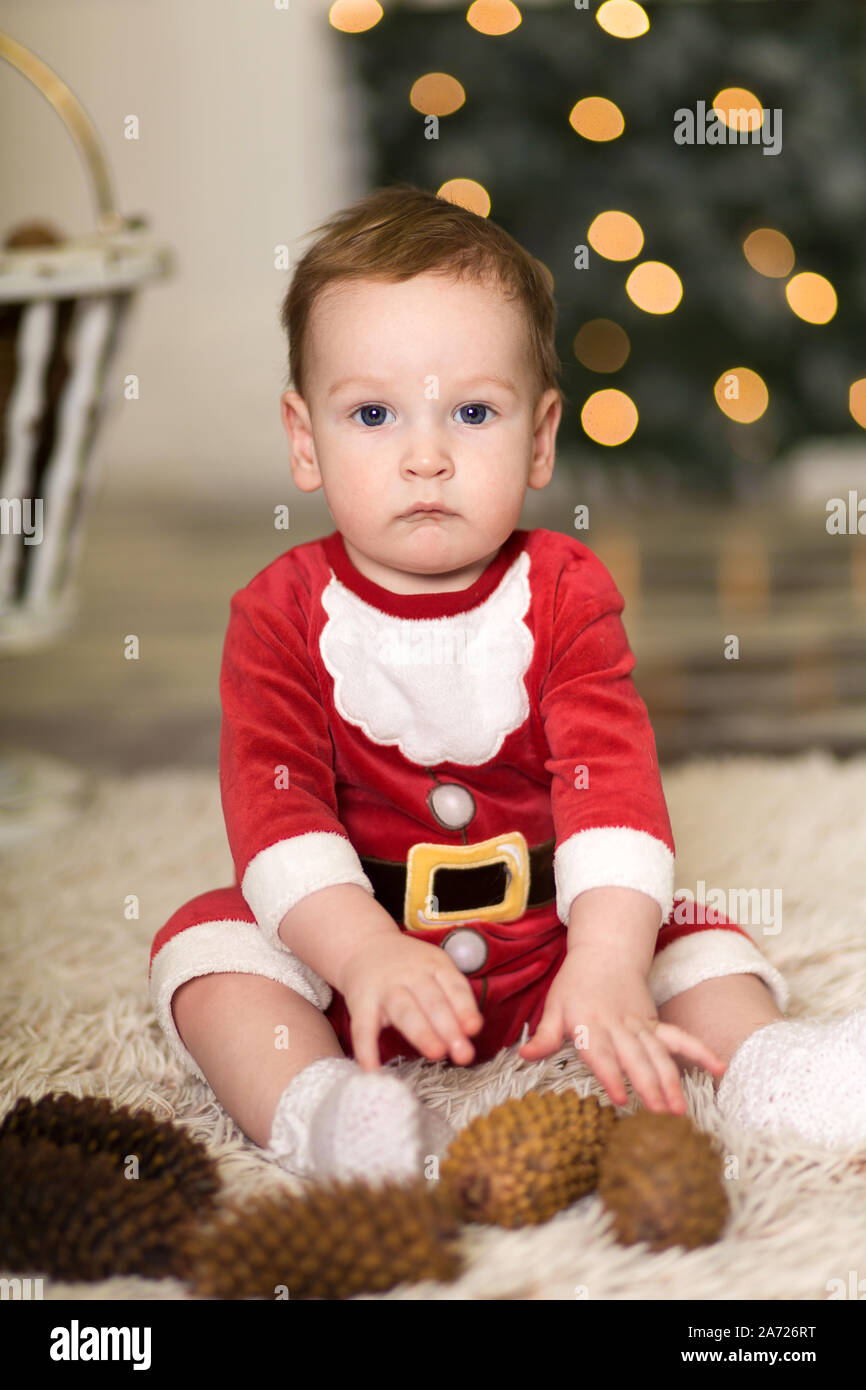 Ritratto di un simpatico bimbo giocando sul pavimento con i coni per decorare l'albero di Natale. Nei pressi della struttura ad albero di Natale e le scatole con i regali di Natale. Mer Foto Stock