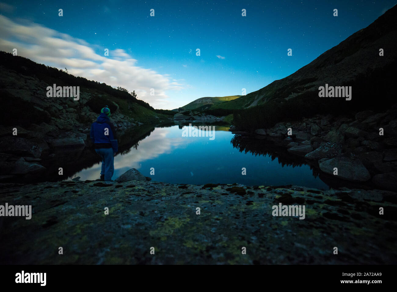 Uomo in piedi sulla riva del lago di notte, disegno Sipritual energia dalla natura e l'universo Foto Stock