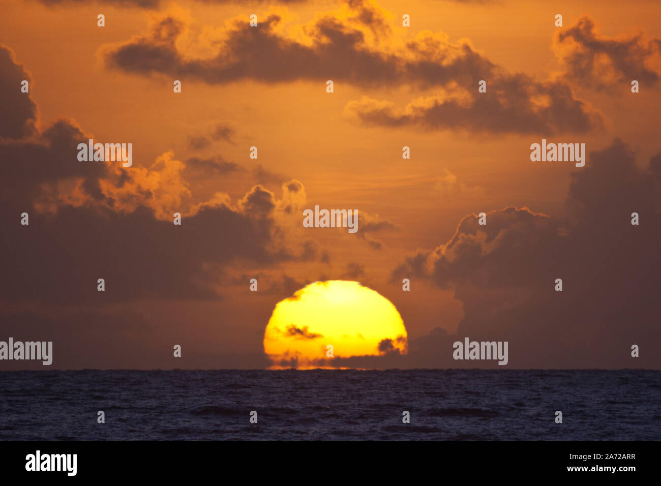 Teleobiettivo con immagine del sole che sorge su un orizzonte di mare Foto Stock