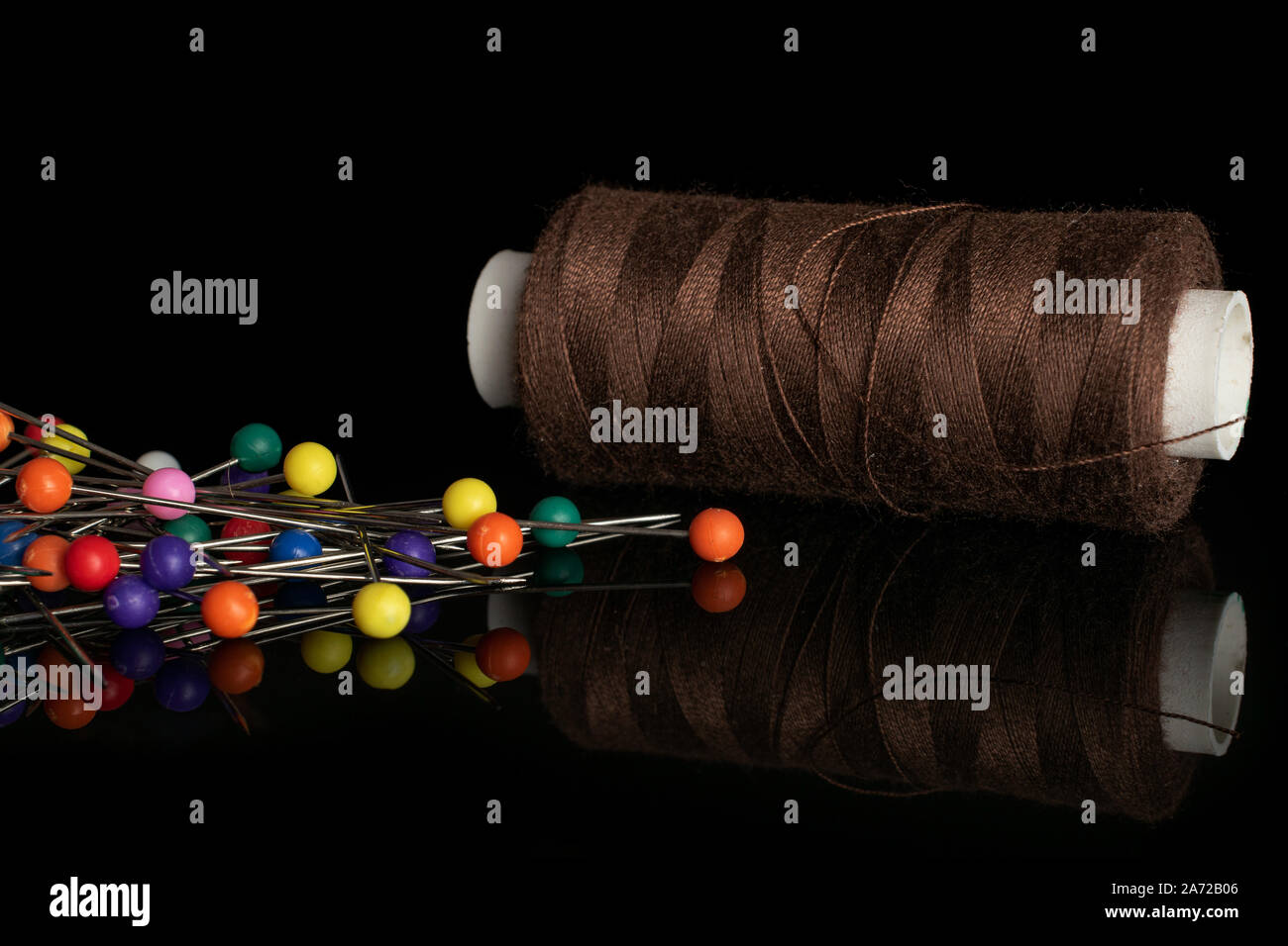 Tutta una merceria articolo uno stelo con aghi isolato sul vetro nero Foto Stock