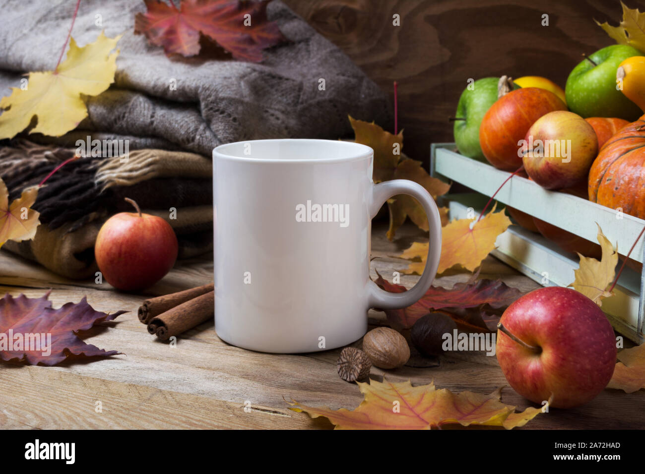 White tazza da caffè mockup con maglia plaid, acero cadono le foglie e le mele. Boccale vuoto mock up per la promozione del design. Foto Stock