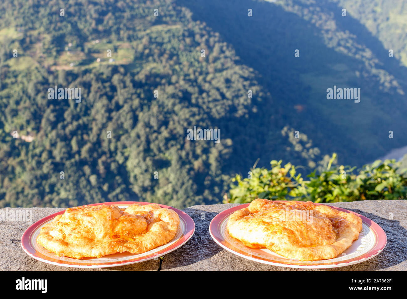 Numtrak balep, Tibetano profonda pane fritto su due piastre, con vista montagna. Colazione popolare durante il trekking in Himalaya, Nepal. Foto Stock