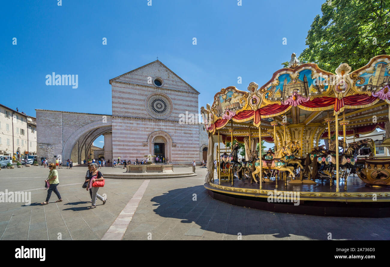 Giostra Antica merry-go-round su Piazza Santa Chiara con vista della facciata della Basilica di Santa Chiara ad Assisi, Umbria, Italia Foto Stock