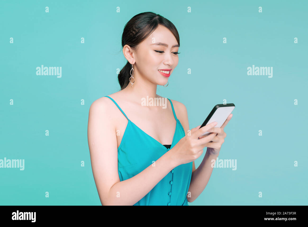 Donna attraente utilizzando messaggi di testo sul suo dispositivo portatile in studio Foto Stock