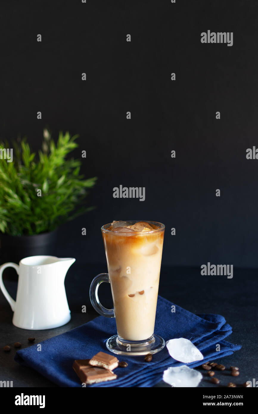 Caffè ghiacciato in un bicchiere con la crema su sfondo nero. Caffè freddo con cubetti di ghiaccio e crema. Foto Stock