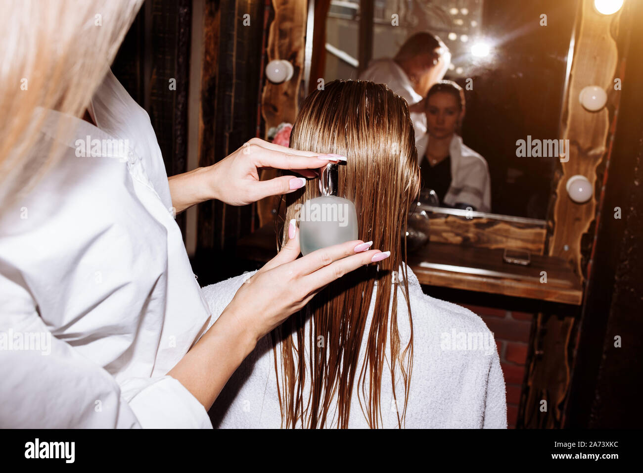 Cura dei capelli nel moderno salone di bellezza. Parrucchiere applicazione spray sulla tipologia dei capelli del cliente. Foto Stock