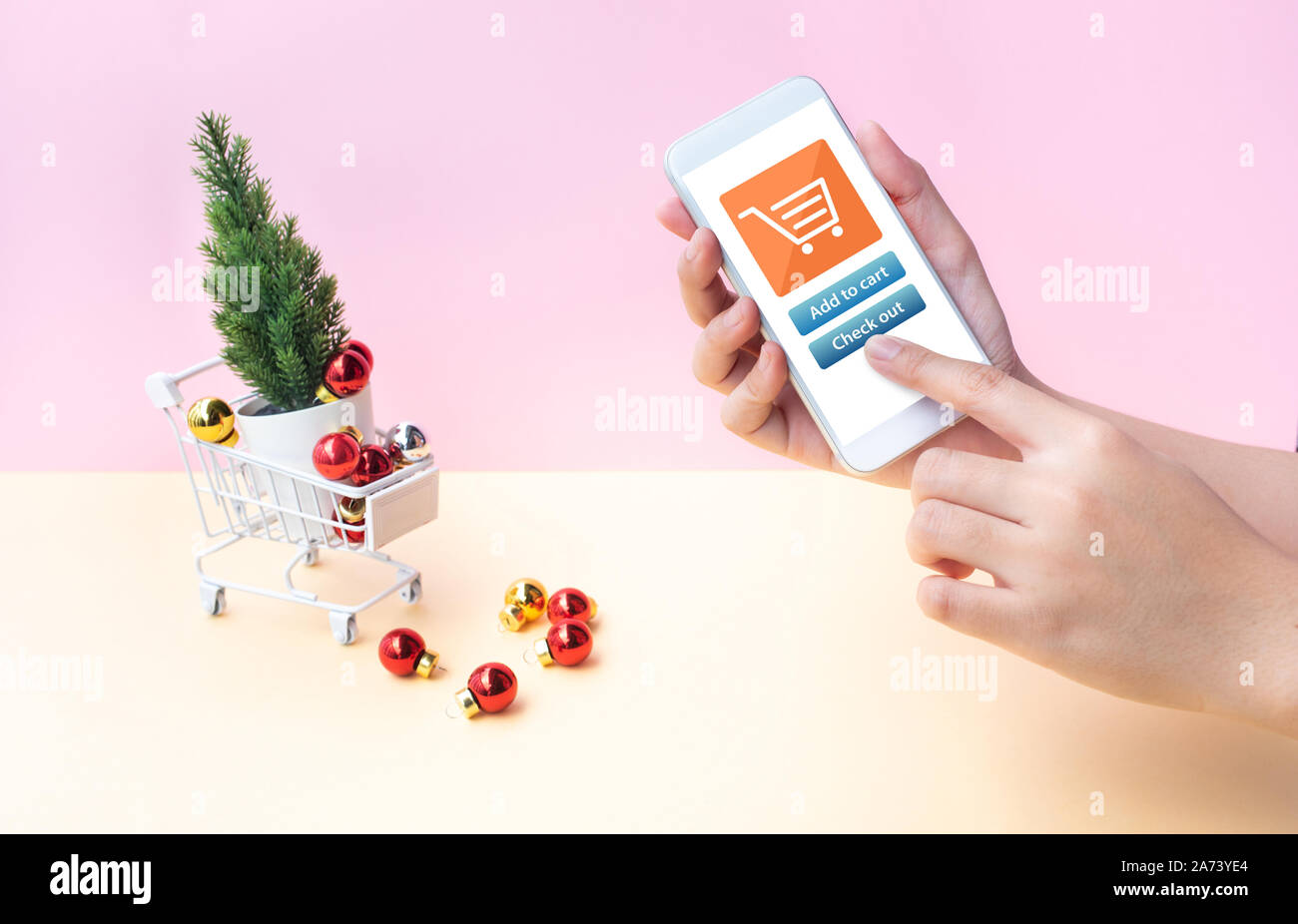 Shopping online su inverno,natale concetti con giovani di sesso femminile che mostra lo smartphone e ornamento di Natale nel carrello laterale,carrello su tutti i sui colori pastello Foto Stock