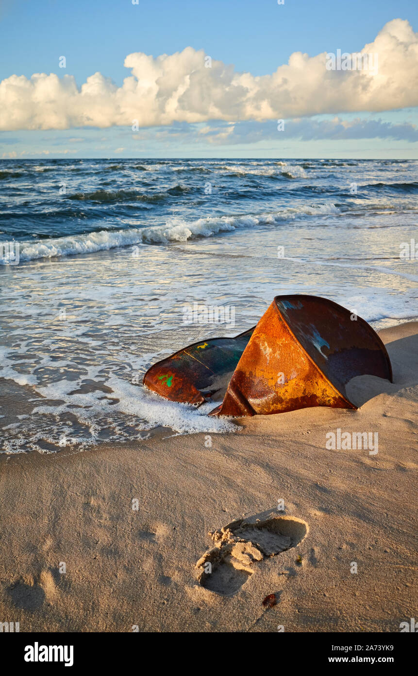Barile arrugginito sulla spiaggia al tramonto, ambiente inquinamento concetto. Foto Stock